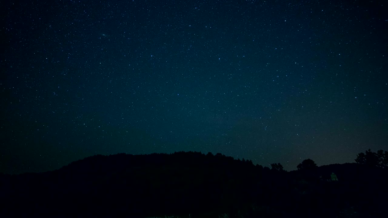 구름과 별들이 산 뒤를 지나가는 밤하늘의 시간 경과