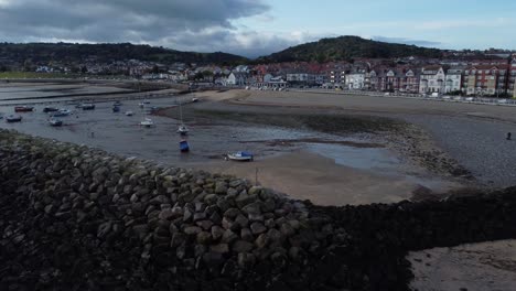 North-Wales-seaside-town-coastline-hotels-harbour-aerial-view-reverse-above-breakwater-rocks