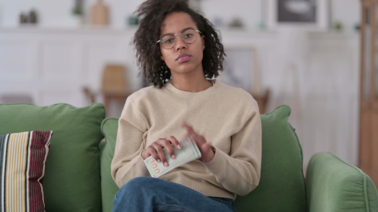 Successful African Woman Counting Dollar on Sofa