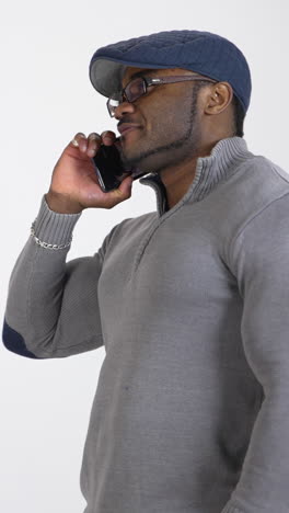 smiling sportsman talking the phone in studio. young afro american man with muscular body having a conversation and smiling. profile view. copy space. vertical video