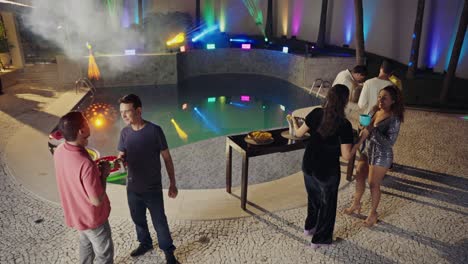 friends celebrating at a vibrant night pool party with laser lights and an lgbtq+ flag