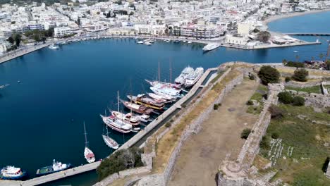 cinematic circular aerial shot of harbor and castle ruins in greek island during sunny day