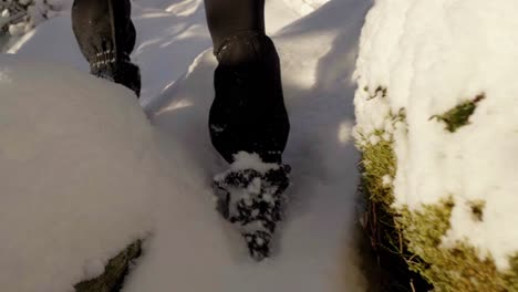 woman hiking snowy hill with snow-chains and gaiters on shoes, handheld slow motion