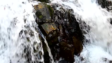 footage of fast water flowing over rocks in the mountain