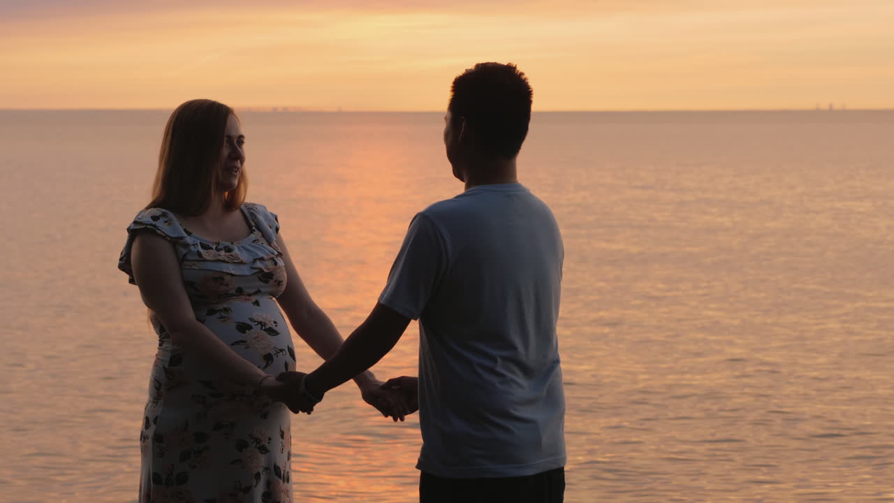 아시아 남자와 임신한 아내의 손을 잡고 있는 젊은 부부