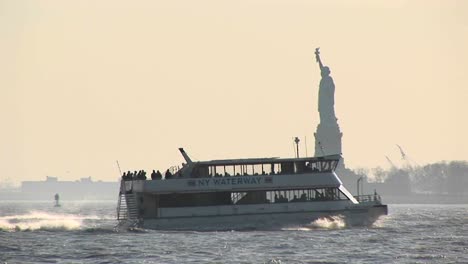 passenger ferries pass each other in new york harbor with the statue of liberty in the background