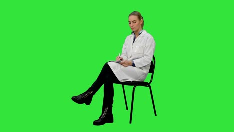 médico femenino hablando con un paciente y escribe en un cuaderno en una pantalla verde, clave de croma