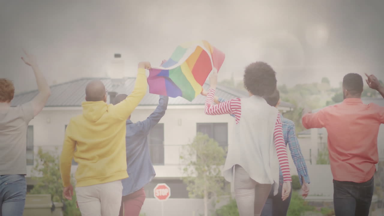 Waving rainbow flag, diverse group walking down suburban street with animation