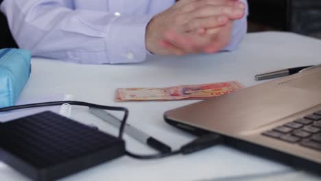 Businessman-Counting-One-Thousand-Argentine-Peso-Paper-Bills-In-The-Table