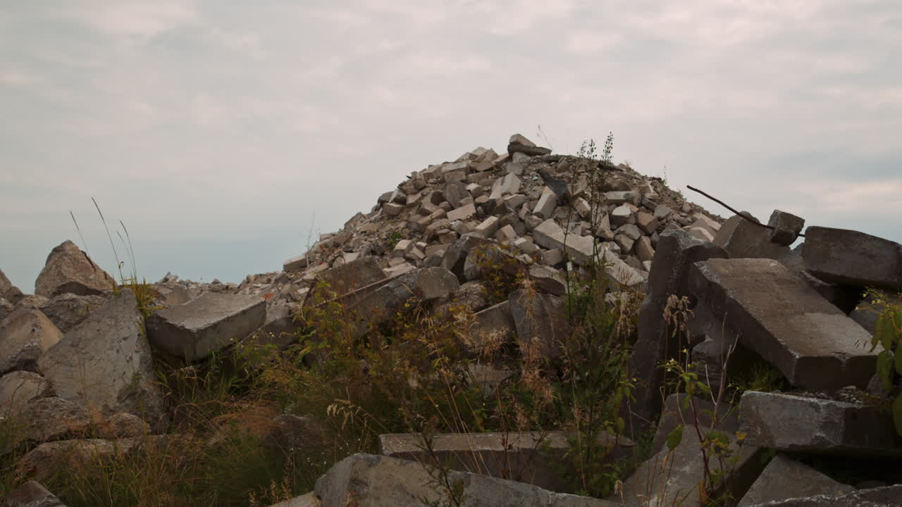 Weeds grown over the huge pile of demolition waste. Stone and concrete blocks in a heap