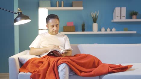 hombre leyendo un libro mientras está acostado.