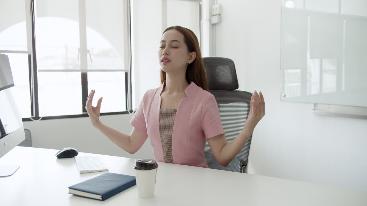 A woman practices mindfulness at her desk promoting relaxation and focus in a busy work environment.