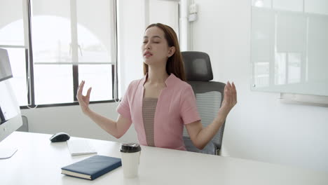 a woman practices mindfulness at her desk promoting relaxation and focus in a busy work environment.