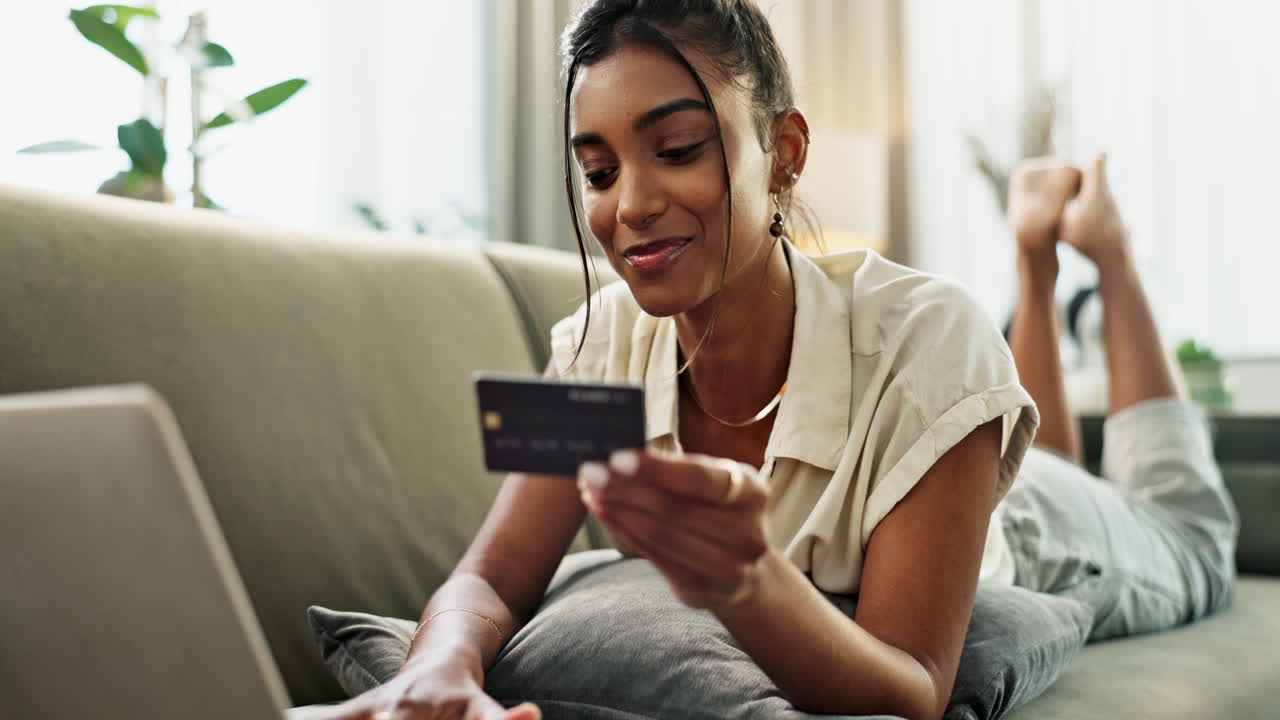 Woman, credit card and laptop on sofa