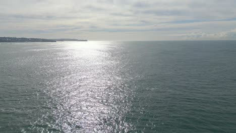 Vuelo-Sobre-El-Mar-Y-El-Océano-Con-Reflejos-De-Sol-En-La-Mañana