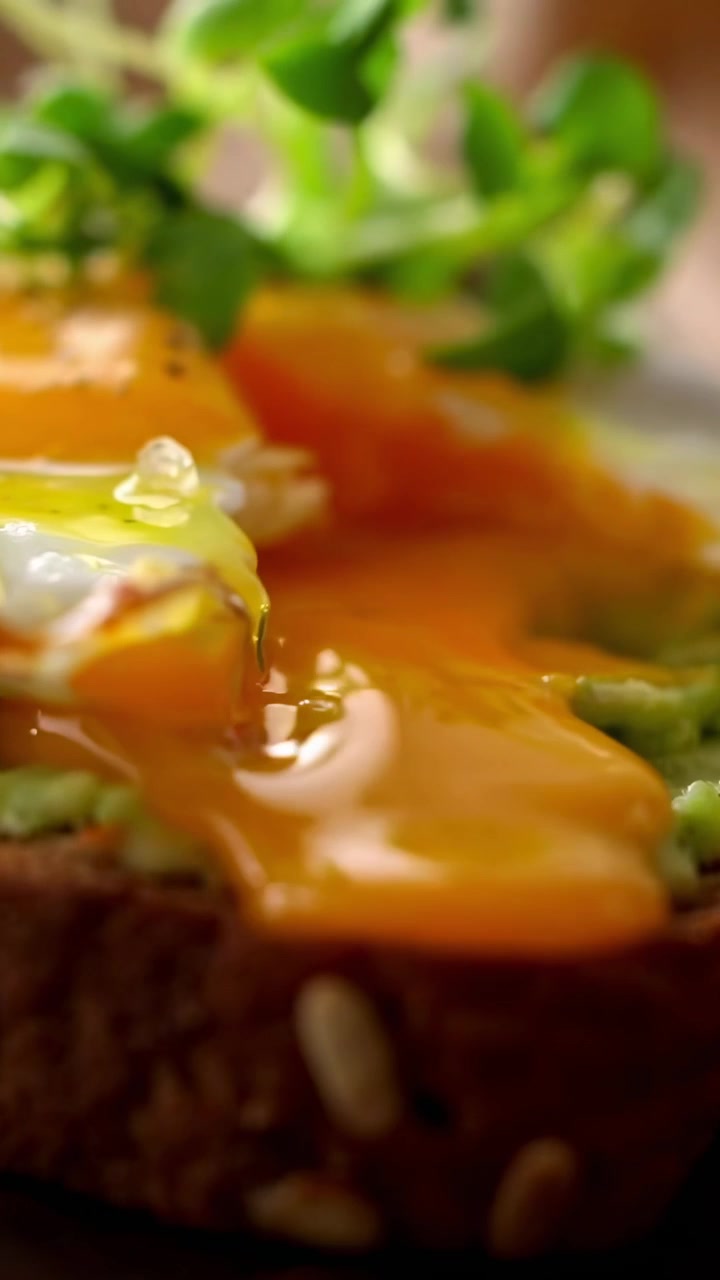 Preparazione di delizioso toast con avocado e un uovo fritto dal tuorlo morbido