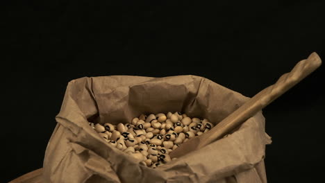 wooden spoon in paper bag of dried black-eyed peas, isolated on black