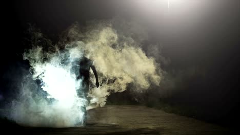 the man going in the cloud of smoke on the dark background, slow motion