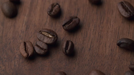 los granos de café tostados caen sobre una mesa de madera