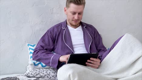 Man Using Tablet in Pajamas on a Bed