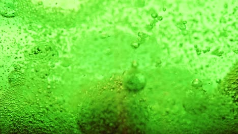 macro shot of green bubbles dripping and moving around in bright green water