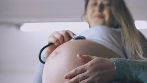 una mujer embarazada usa un estetoscopio para examinar al bebé en el vientre