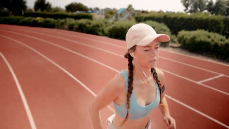 young fit woman listening to music and running on track