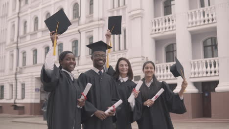 grupo multicultural de estudiantes graduados lanzando sus gorras al aire