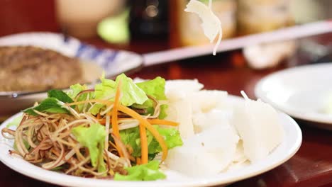 chopsticks adding ingredients to vietnamese noodle dish