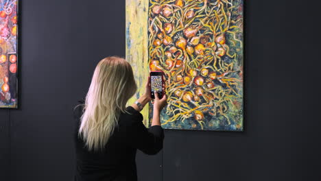 woman taking picture of paintings in an art gallery