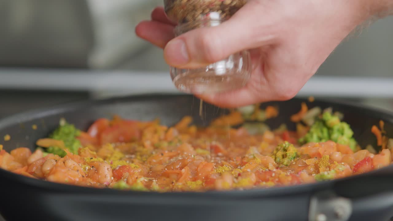 hombre condimentando frijoles y verduras en una fritura
