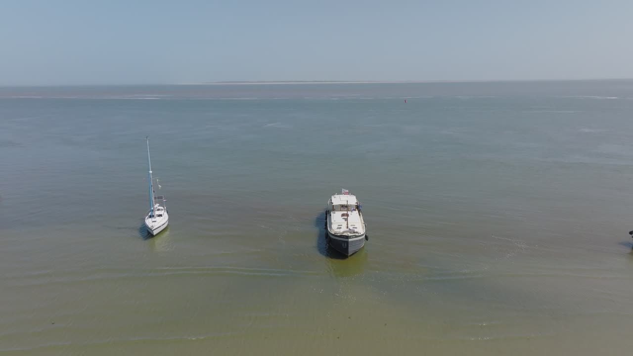 Wide frontal aerial of mixed boats spread across calm green open water near tidal flats; schooner, luxemotor and yachts visible. Wadden Sea
