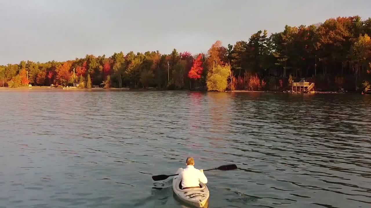 kayakista remando a lo largo de la costa del lago michigan durante los colores del otoño