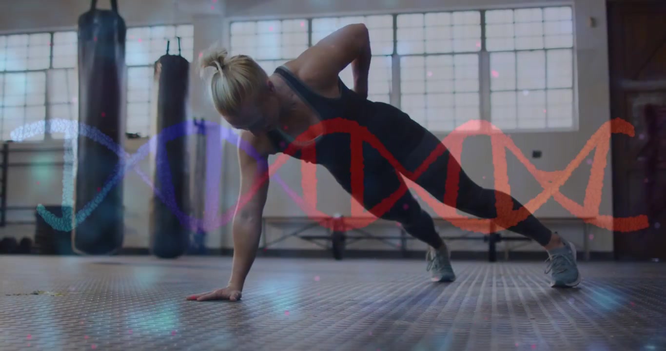 Woman performing one-arm plank rotating from right arm base in gym particles and helix aiding core