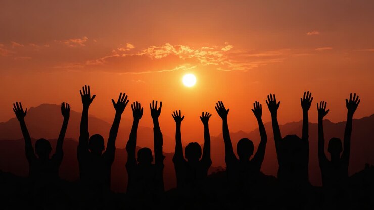 Silhouettes Against a Vibrant Sunset: A Group of People Celebrating with Raised Hands in a Scenic Mountain Landscape