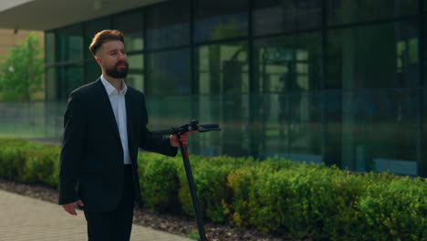 businessman riding an electric scooter in front of modern building