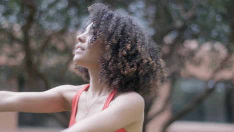 curly-haired woman stretching on the edge of the garden with the sun shining brightly in the morning