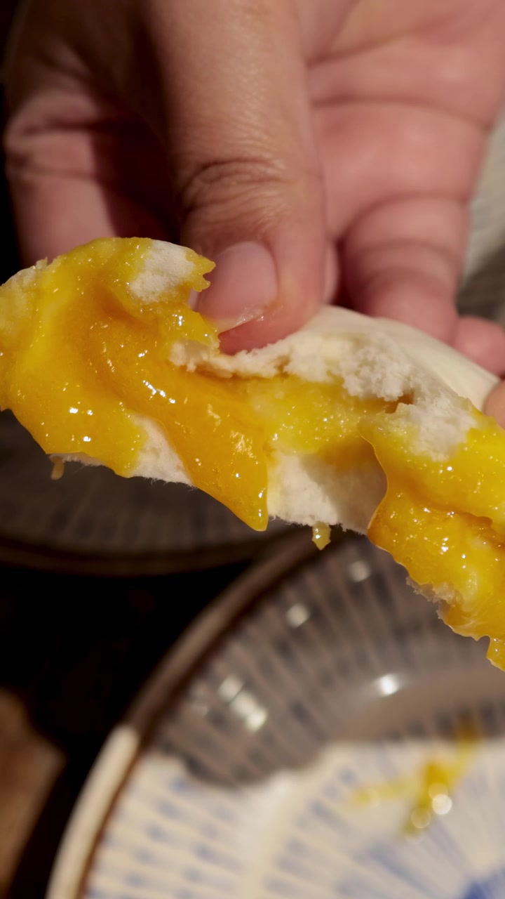 Hands reveal filling of steamed bun