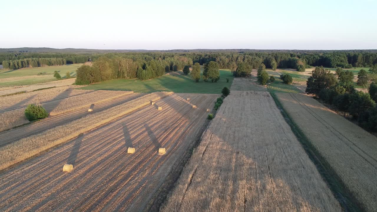 blick auf den sonnenuntergang aus der luft auf die weizenplantage mit heuballen auf dem ackerland während der goldenen stunden