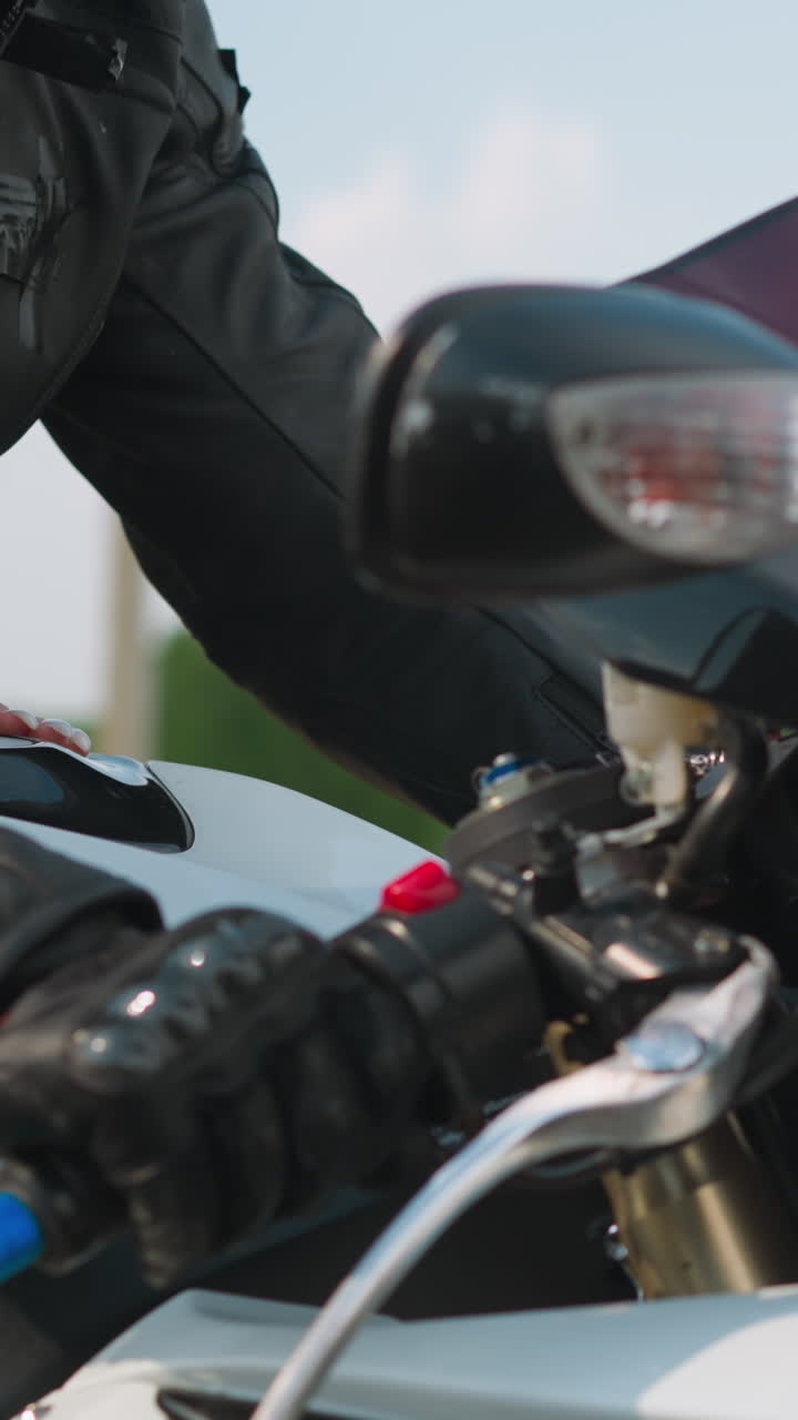 Graceful woman hugs beloved boyfriend motorcyclist riding motorbike along road past green field at country site extreme closeup slow motion