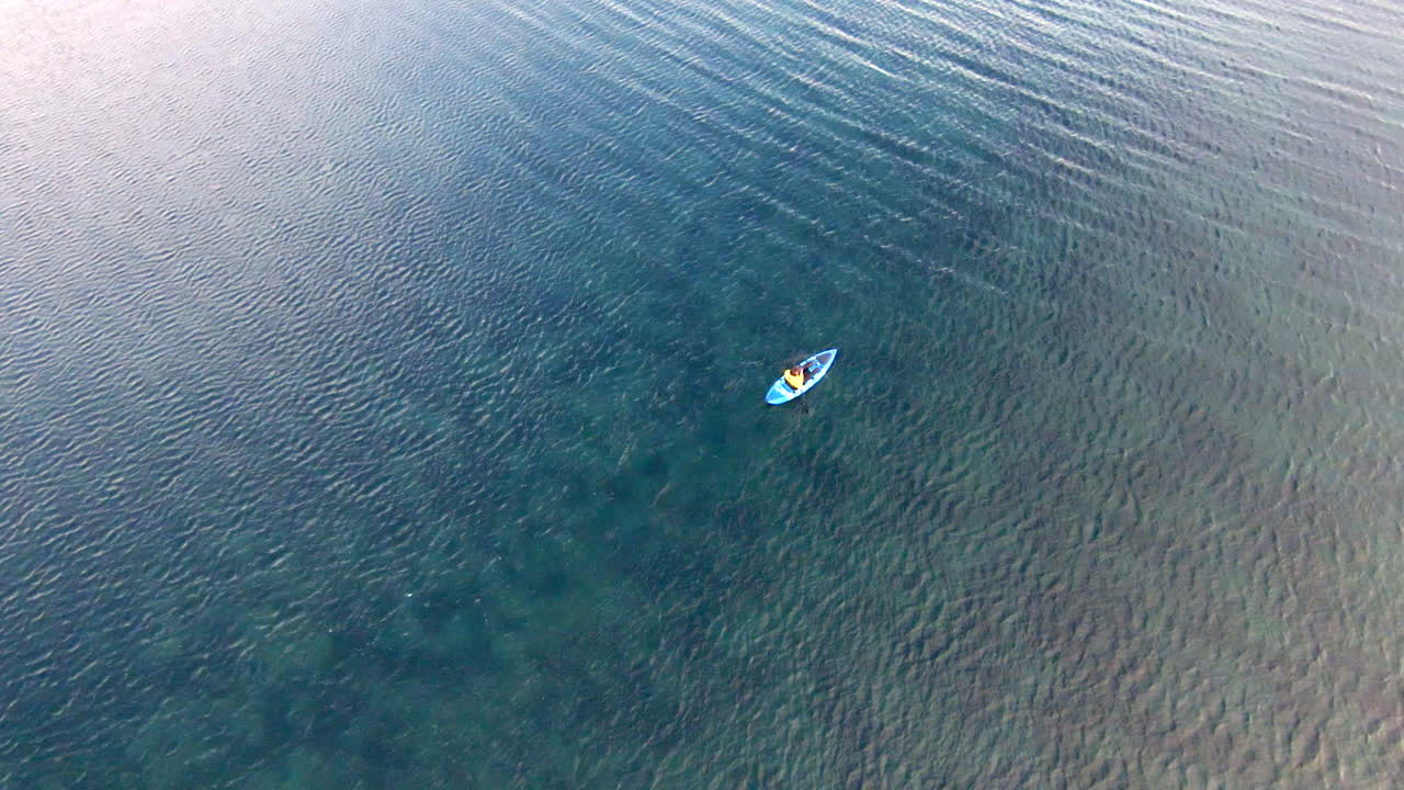 파란 카야크가 파란 물 위에서 떠다니고 있습니다.