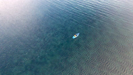 From-above-blue-kayak-floating-on-wavy-clear-water