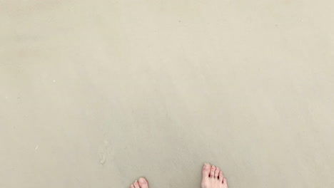 ocean waves wash over beach and feet, first person pov