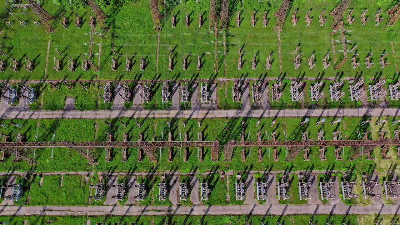 High voltage lines on green field. Flight over power transmission lines. Huge territory with steel pillars for electricity. Top aerial view.