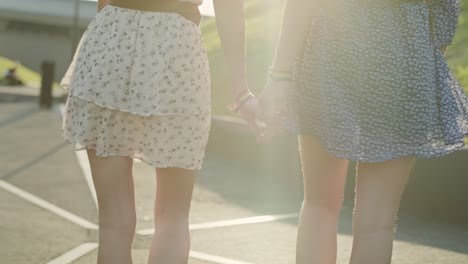 handheld video of two unrecognizable women walking and holding hands