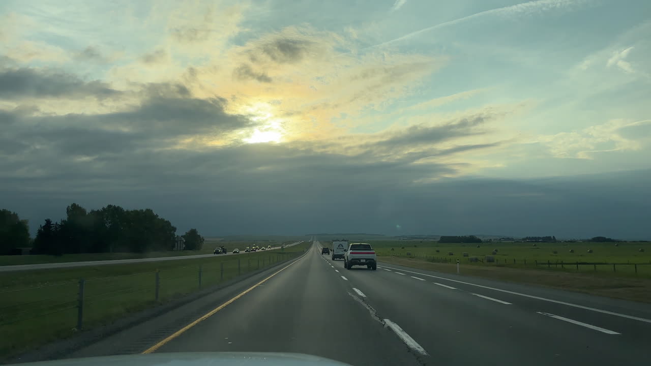 Driving along highway at sunset. Banff, Alberta, Canada. Real time, driver POV