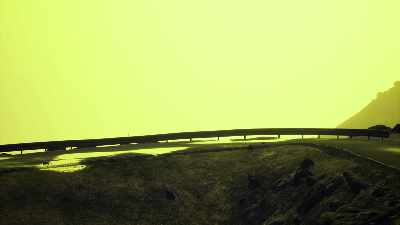 Road curving along hillside under unusual yellow sky with dramatic atmosphere