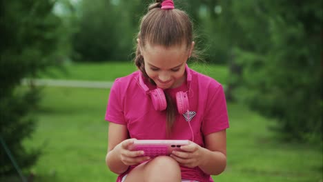 young girl enjoying interactive play with handheld device surrounded by nature, showcasing joy and engagement in outdoor activities