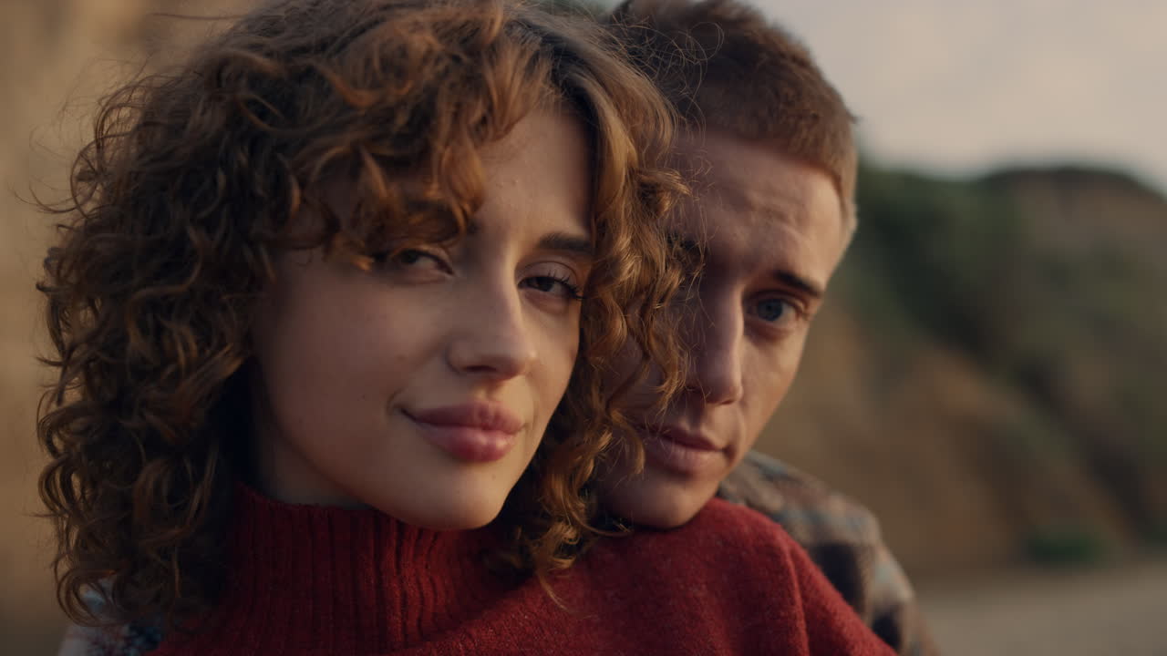 улыбающаяся пара смотрит в камеру. веселая женщина и мужчина позируют на пляже.