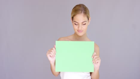 mujer rubia atractiva sosteniendo un letrero verde en blanco